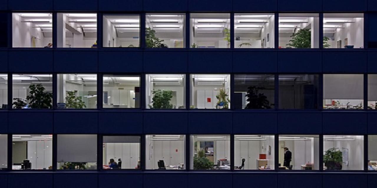 Viele Fenster eines Hochhauses, die nachts beleuchtet sind.